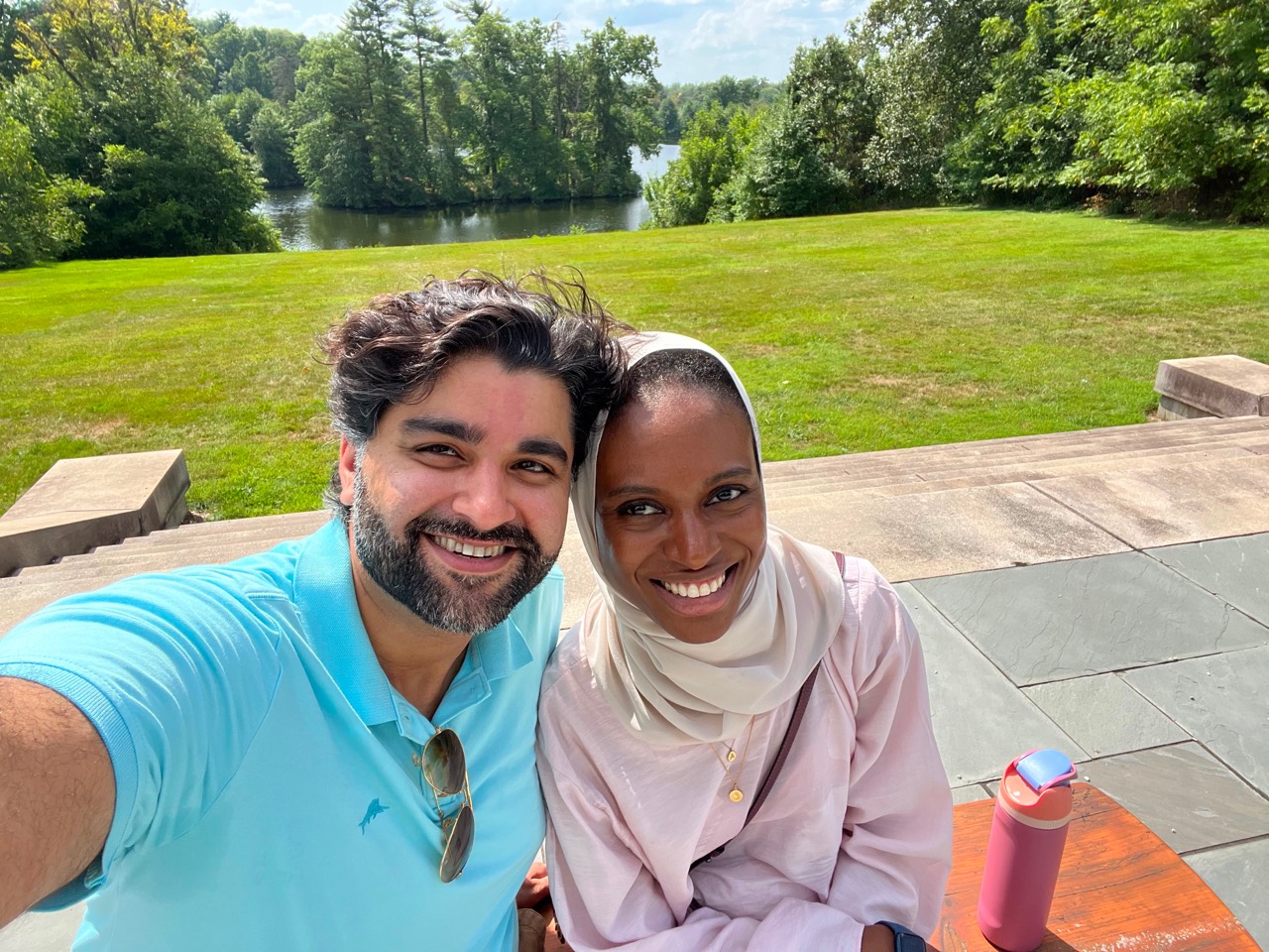 Amal and Usman smiling together beside the water